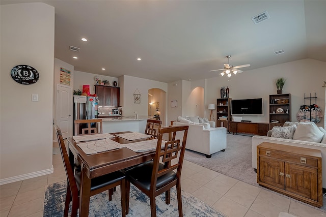 dining space with light tile patterned floors, arched walkways, a ceiling fan, and visible vents