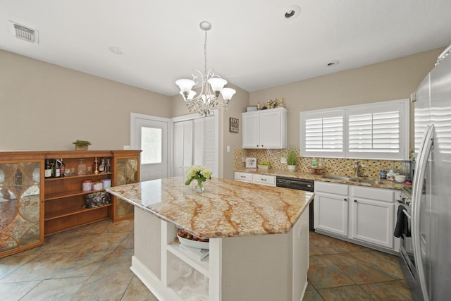 kitchen featuring tasteful backsplash, dishwasher, a sink, freestanding refrigerator, and a notable chandelier