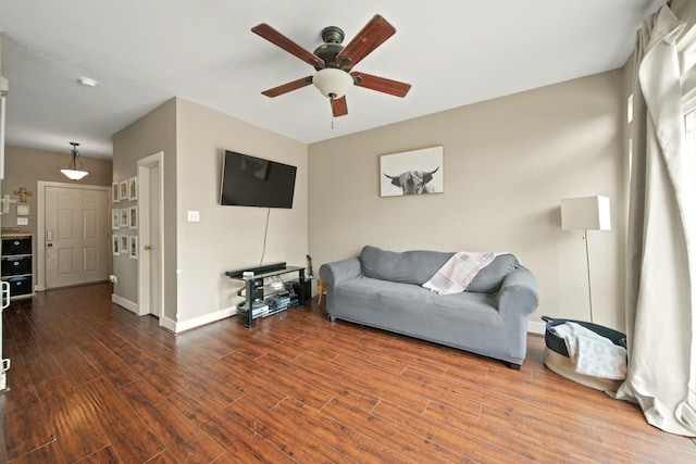 living area with baseboards, ceiling fan, and wood finished floors