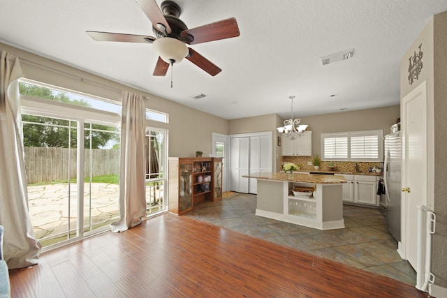 kitchen featuring white cabinets, open shelves, a center island, backsplash, and visible vents