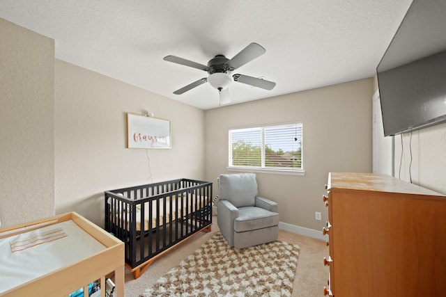 bedroom featuring baseboards, ceiling fan, carpet, and a nursery area