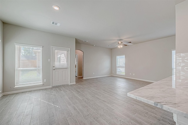 27083 Badger Way, Magnolia, TX 77354 - unfurnished living room with arched walkways, a ceiling fan, light wood-style flooring, and visible vents