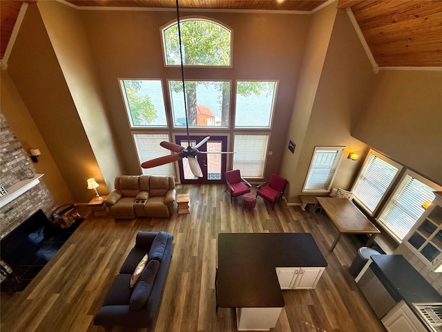 interior space featuring ceiling fan, a towering ceiling, a tiled fireplace, wood finished floors, and wooden ceiling