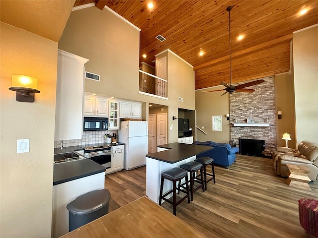 kitchen with freestanding refrigerator, dark countertops, black microwave, and stainless steel electric stove