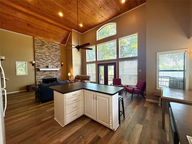 kitchen featuring dark countertops, a fireplace, wooden ceiling, white cabinets, and high vaulted ceiling