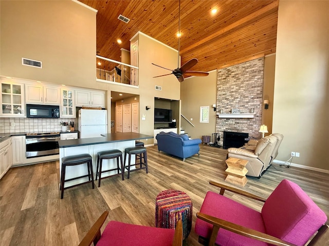 living room with high vaulted ceiling, visible vents, wooden ceiling, and ceiling fan