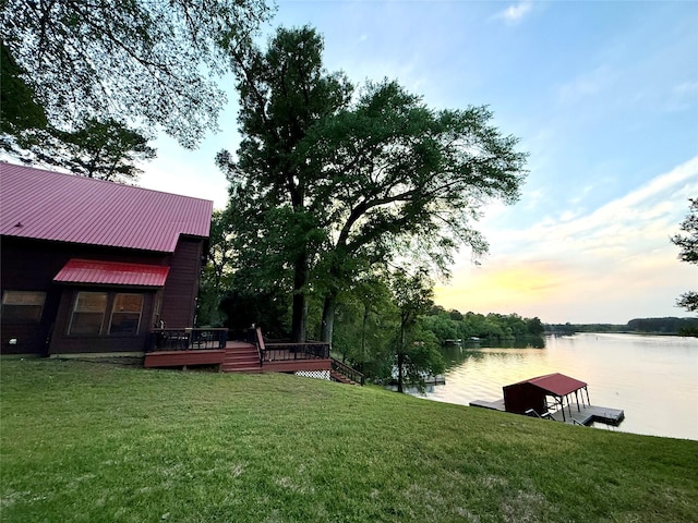 yard at dusk with a water view and a dock
