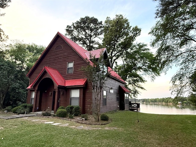 view of front of home with a water view, a front yard, and metal roof