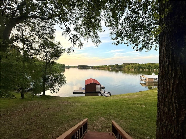view of dock with a yard and a water view