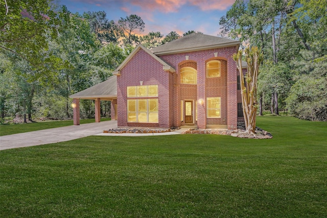 view of front of property featuring brick siding, a front lawn, concrete driveway, a shingled roof, and an attached carport