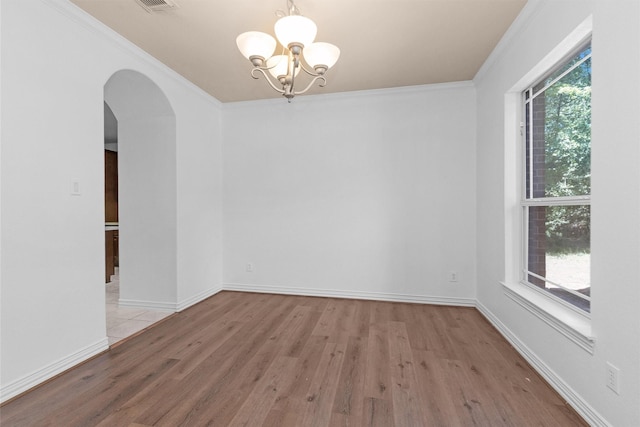 unfurnished room featuring arched walkways, wood finished floors, baseboards, a chandelier, and ornamental molding