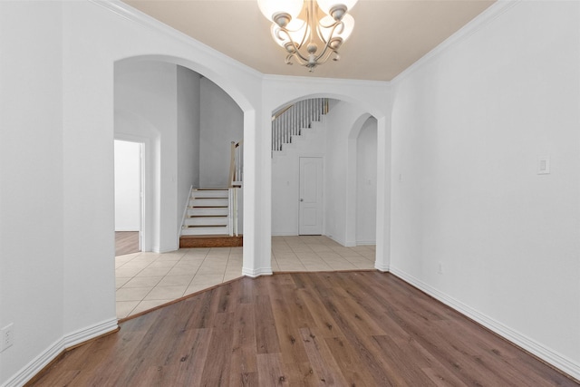 interior space with crown molding, stairs, wood finished floors, a chandelier, and arched walkways