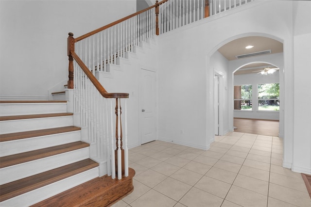 9019 Miller Rd, Magnolia, TX 77354 - stairway with tile patterned floors, arched walkways, a towering ceiling, and baseboards