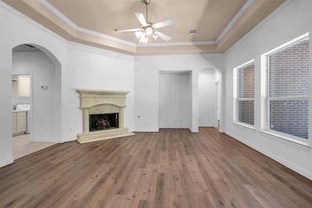 unfurnished living room featuring arched walkways, ceiling fan, wood finished floors, and visible vents