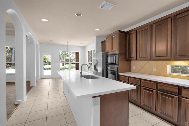 kitchen featuring a sink, light tile patterned floors, backsplash, visible vents, and black appliances