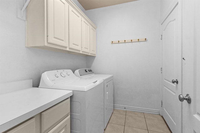 washroom featuring light tile patterned floors, baseboards, independent washer and dryer, and cabinet space