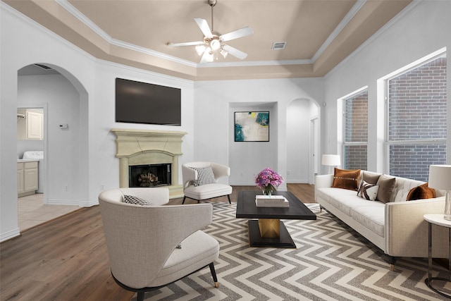 9019 Miller Rd, Magnolia, TX 77354 - living area with arched walkways, a ceiling fan, light wood-style flooring, ornamental molding, and a fireplace with raised hearth