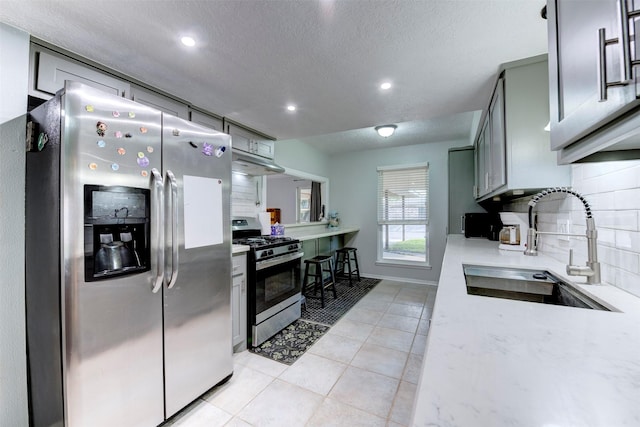 4114 Cicada Ln, Houston, TX 77039 - kitchen featuring light countertops, a textured ceiling, tasteful backsplash, a sink, and stainless steel appliances