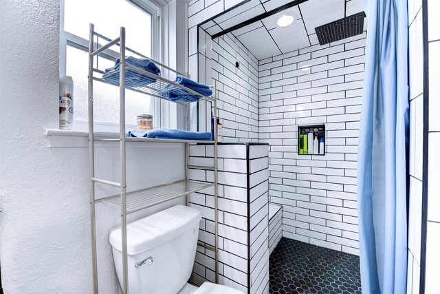 4114 Cicada Ln, Houston, TX 77039 - bathroom with toilet, a textured wall, a tile shower, and a healthy amount of sunlight