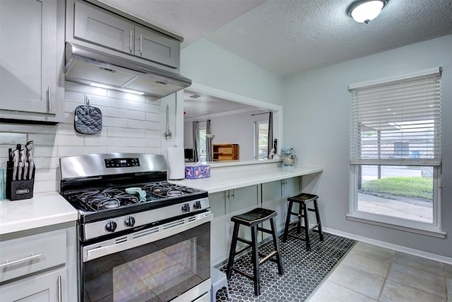 4114 Cicada Ln, Houston, TX 77039 - kitchen featuring light countertops, stainless steel gas range oven, under cabinet range hood, and tasteful backsplash