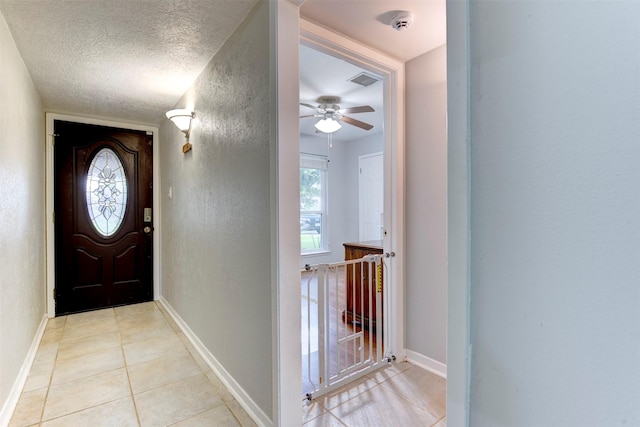 4114 Cicada Ln, Houston, TX 77039 - foyer with baseboards, a ceiling fan, a textured wall, and light tile patterned floors