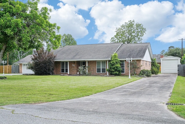 ranch-style house featuring brick siding, an outdoor structure, a detached garage, concrete driveway, and a front lawn