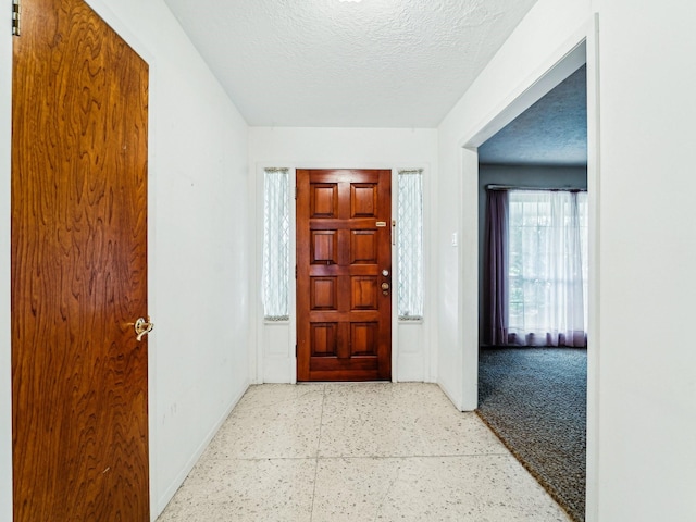 entrance foyer featuring a textured ceiling and baseboards