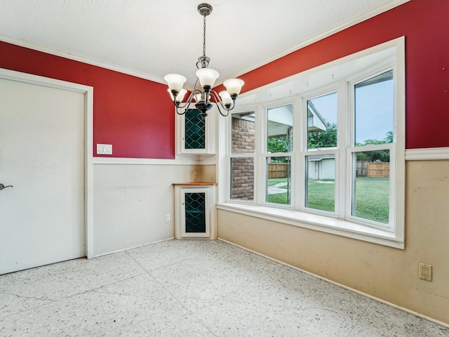 unfurnished living room featuring baseboards, an inviting chandelier, crown molding, and speckled floor