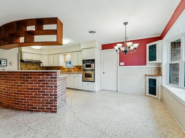 kitchen with stainless steel double oven, pendant lighting, a notable chandelier, baseboards, and backsplash