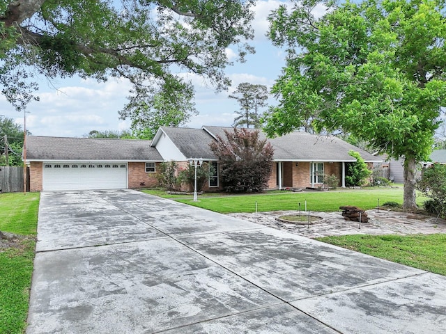 ranch-style home featuring a garage, fence, concrete driveway, a front lawn, and brick siding