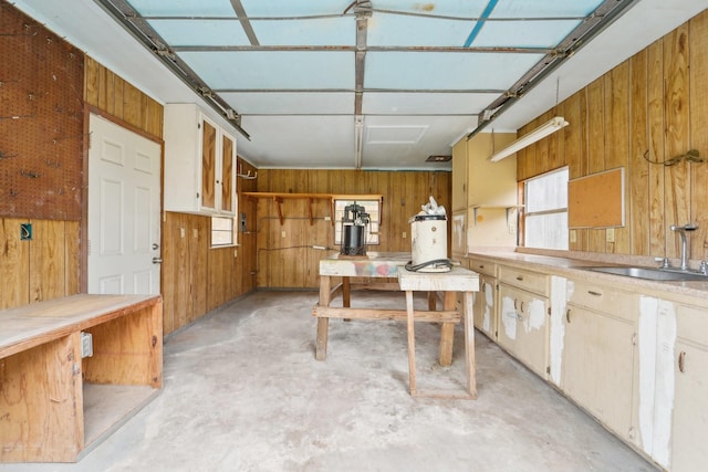 interior space featuring unfinished concrete floors, wood walls, and a sink
