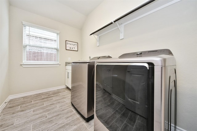 washroom with washer and clothes dryer, cabinet space, light wood-style flooring, and baseboards