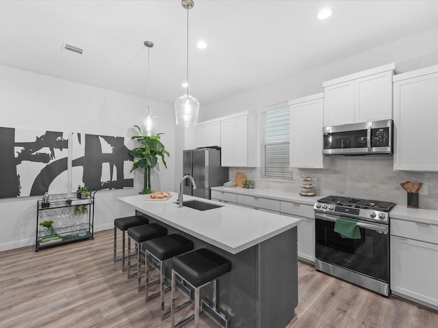 kitchen featuring visible vents, a kitchen breakfast bar, a sink, light wood-style flooring, and appliances with stainless steel finishes