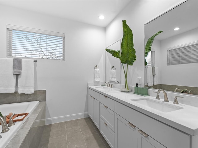 full bathroom with a sink, double vanity, recessed lighting, baseboards, and tiled tub