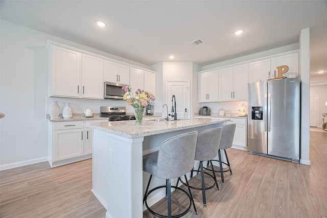 kitchen with stainless steel appliances, light wood-style flooring, visible vents, and a sink