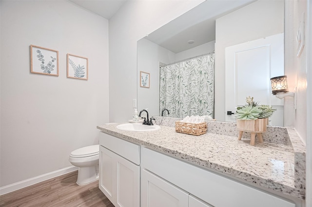 bathroom with toilet, wood finished floors, vanity, a shower with shower curtain, and baseboards