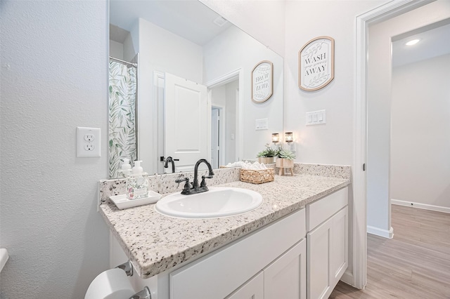 bathroom featuring baseboards, vanity, and wood finished floors