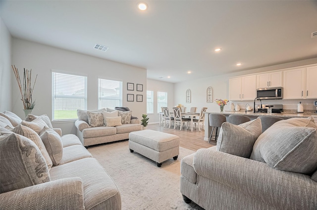 living room with light wood-type flooring, visible vents, and recessed lighting
