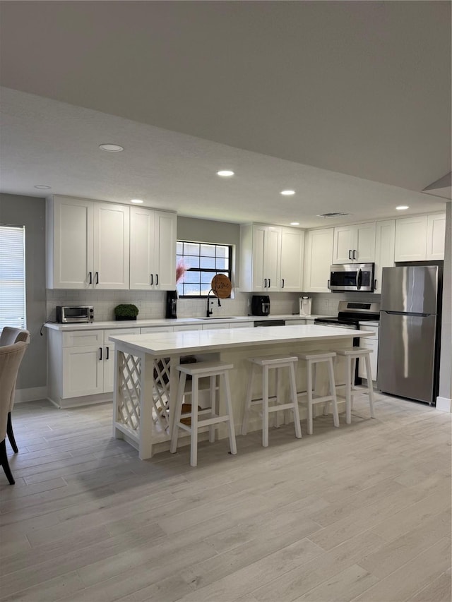 175 Heather Ln, Livingston, TX 77351 - kitchen with a center island, light wood-type flooring, appliances with stainless steel finishes, tasteful backsplash, and recessed lighting