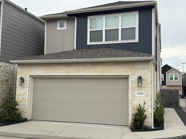 exterior space featuring an attached garage, roof with shingles, stucco siding, and stone siding