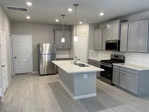 kitchen with a sink, visible vents, stainless steel appliances, tasteful backsplash, and gray cabinetry