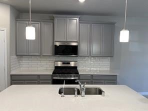 kitchen with gray cabinetry, appliances with stainless steel finishes, a sink, and light countertops