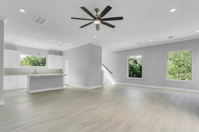 unfurnished living room featuring stairway, ceiling fan, light wood finished floors, and visible vents