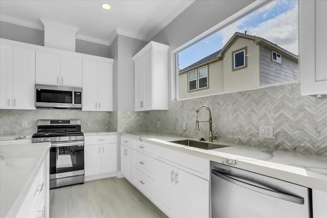 kitchen with backsplash, stainless steel appliances, ornamental molding, and a sink