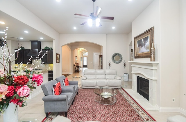 living room with light tile patterned flooring, recessed lighting, arched walkways, a ceiling fan, and a glass covered fireplace