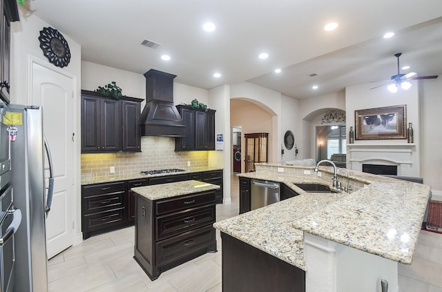 kitchen featuring a spacious island, ceiling fan, a sink, tasteful backsplash, and appliances with stainless steel finishes