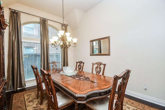 dining space with an inviting chandelier, baseboards, wood finished floors, and lofted ceiling