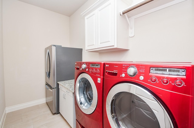 laundry area featuring washing machine and clothes dryer, baseboards, and cabinet space