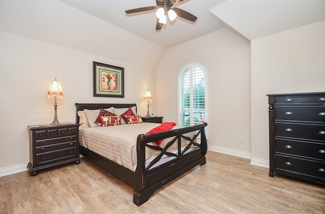 bedroom featuring light wood finished floors, a ceiling fan, baseboards, and lofted ceiling