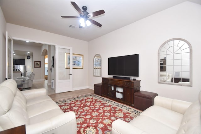 living room with wood finished floors, visible vents, arched walkways, a ceiling fan, and baseboards